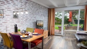 Un comedor moderno con pared de ladrillo, televisión y puerta corrediza de vidrio que da a un patio al aire libre.