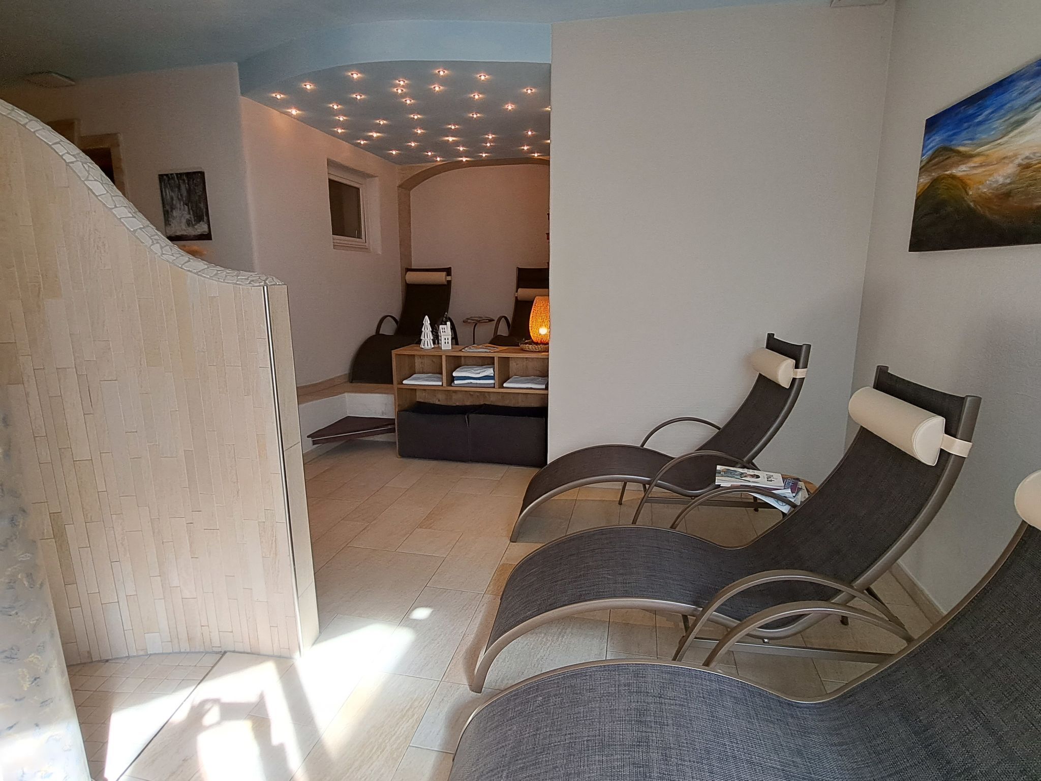 Een spa-ruimte met relaxstoelen, een massagetafel en een plafond met inbouwverlichting.