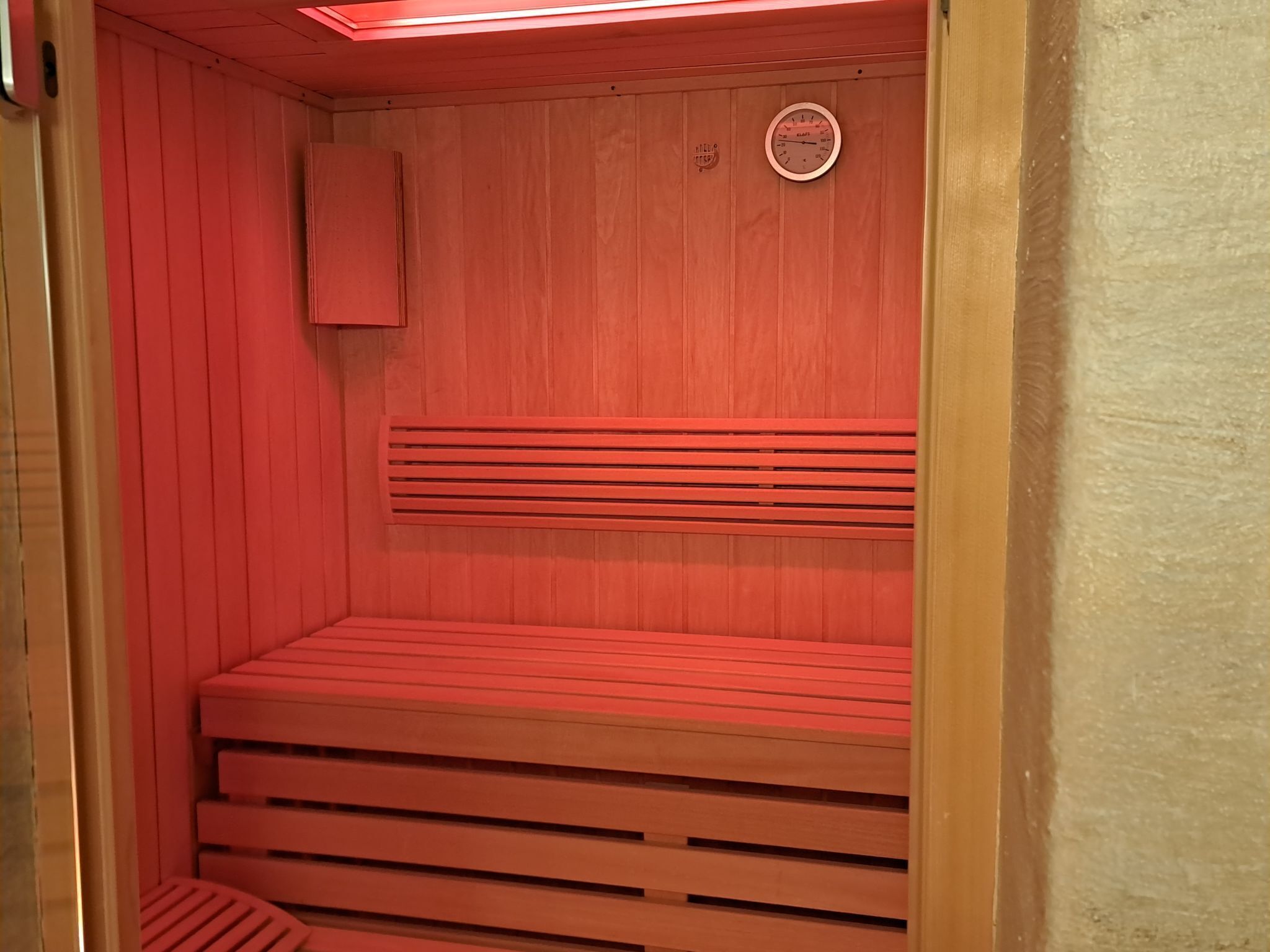 A sauna with wooden benches and a clock on the wall.