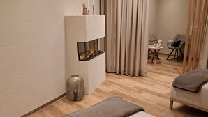 Une chambre d’hôtel moderne avec un plancher en bois, un canapé, une petite table et un vase décoratif.