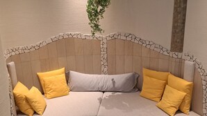 Un canapé incurvé avec une tête de lit qui ressemble à de la pierre et des coussins jaunes.