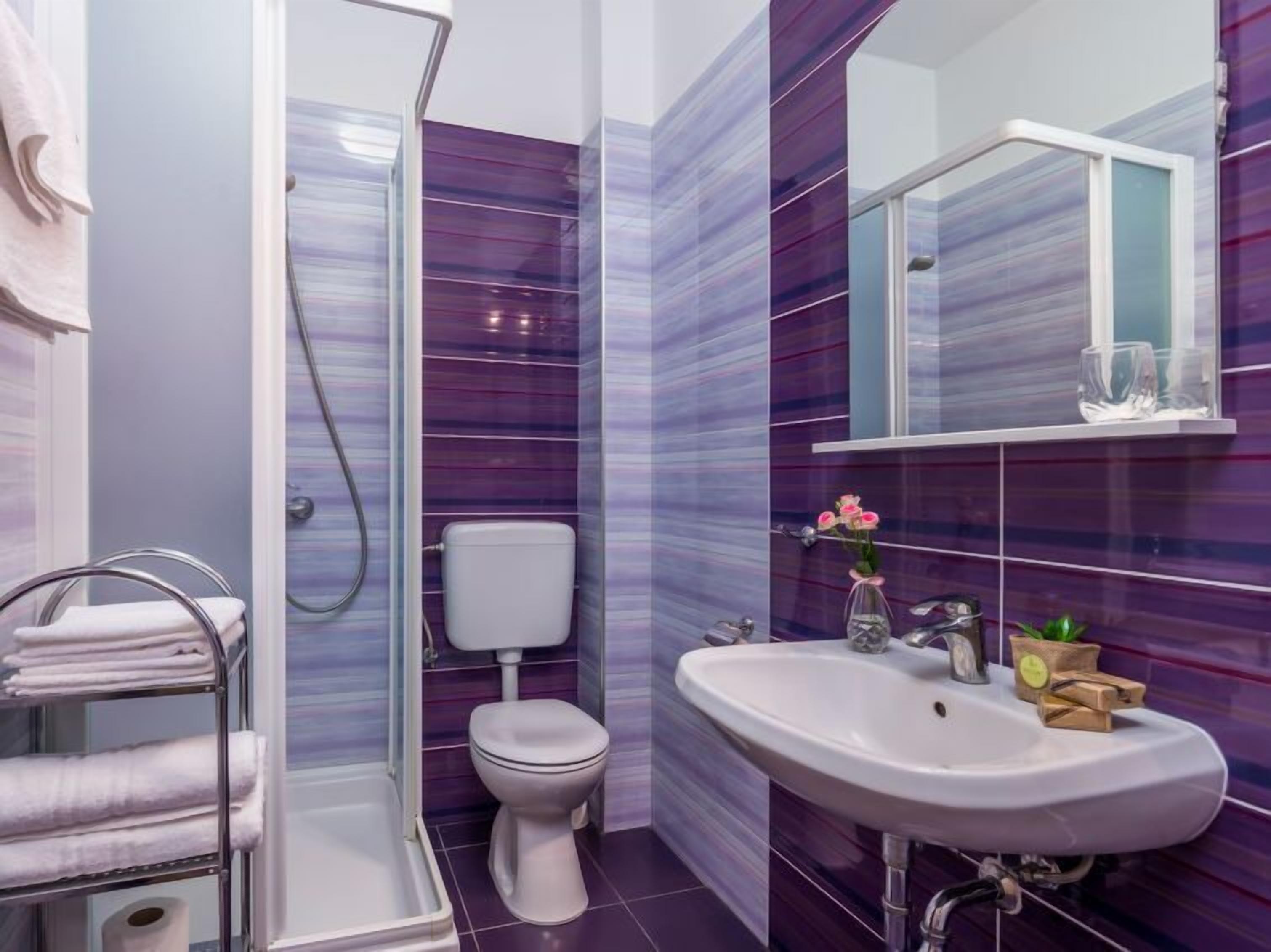A bathroom with a shower, toilet, and sink.