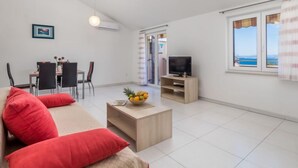 A modern living room with a sofa, coffee table, TV, and dining area. - Apartment Tea by Interhome (Krk/Šilo)