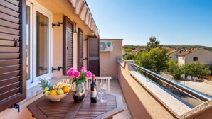 A balcony with a table set for two, a bowl of fruit, and a vase of flowers. - Apartment Tea by Interhome (Krk/Šilo)