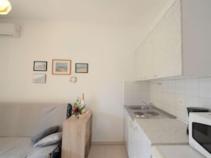 A compact kitchen with a microwave, sink, and a small wooden table with a vase. - Apartment Neda by Interhome (Labin)