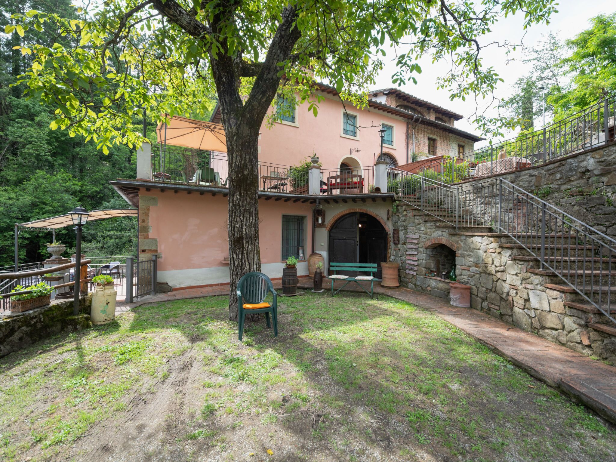 Une villa de style rustique, dotée d’un escalier en pierre, d’un grand arbre et d’un espace salon extérieur.