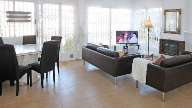 Un salon moderne avec un canapé, des fauteuils, un téléviseur et une cheminée.