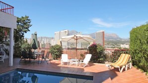 Un espace piscine aménagé sur le toit, avec des chaises longues, une table et des parasols.