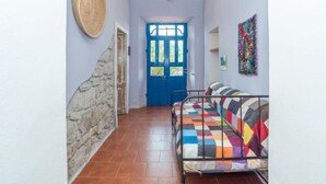 A hallway with a blue door, a stone wall, a bed with a colorful quilt, and a hanging basket. - Camilla by Interhome (Valledoria)