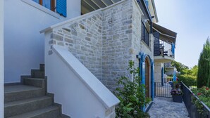 Una escalera de piedra que conduce a un edificio blanco con contraventanas azules y un balcón.