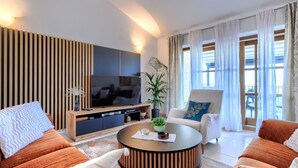 Una sala de estar moderna con un televisor de pantalla plana, una mesa redonda de centro y dos sofás.