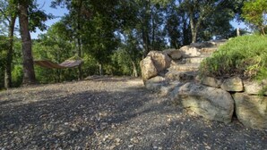 A natural outdoor area with a hammock, large rocks, and dense trees. - Casa la Selvolina by Interhome (Roccastrada)