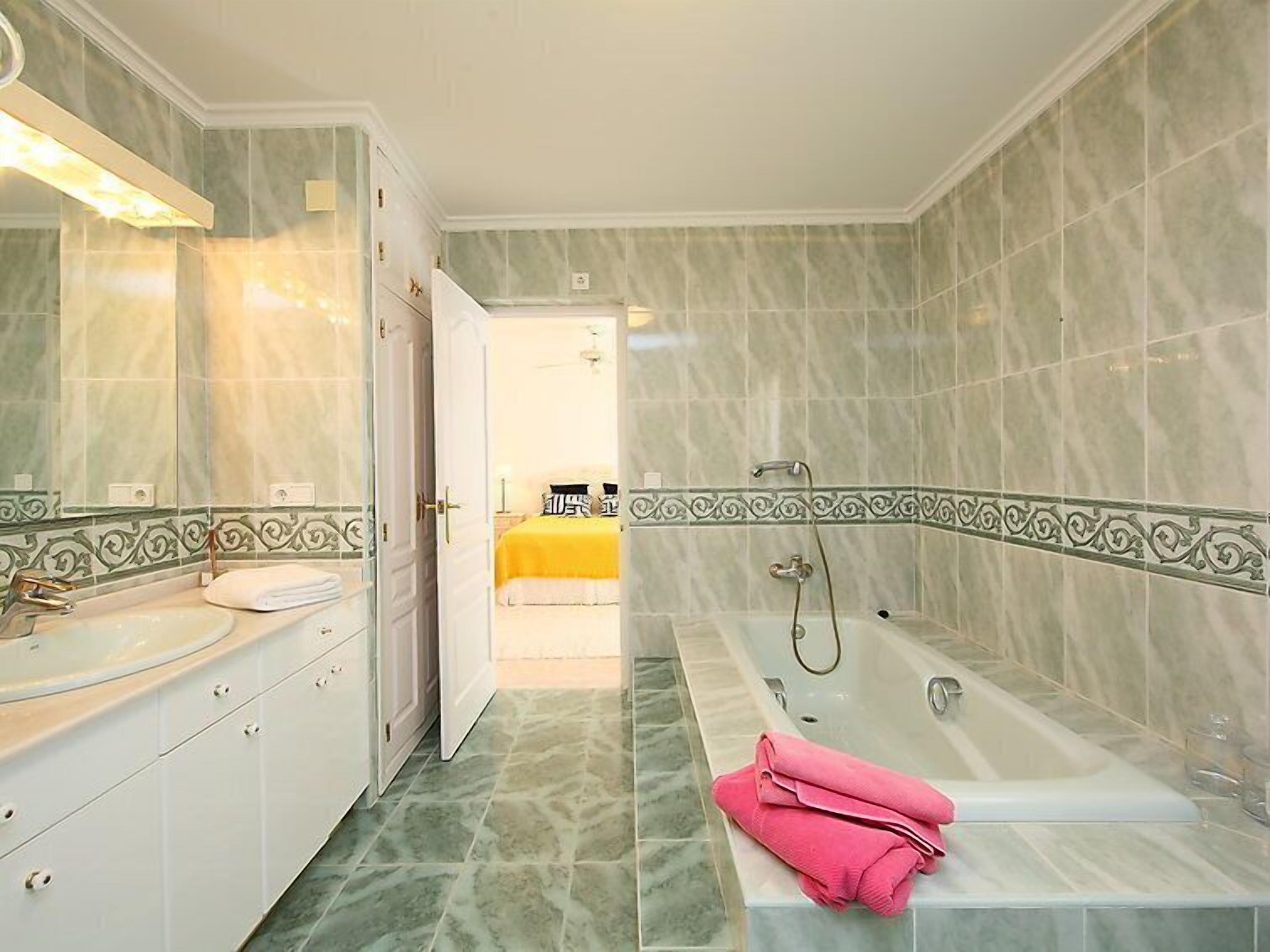 Ein Badezimmer mit Waschbecken, Spiegel, Schminktisch und einer Badewanne mit Handtüchern.
