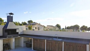 An outdoor kitchen area with a grill, sink, and wooden cabinets. - Perales by Interhome (L'Ampolla)