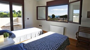 A bedroom with a bed, a desk, a chair, a window with a view, and a ceiling fan. - Perales by Interhome (L'Ampolla)