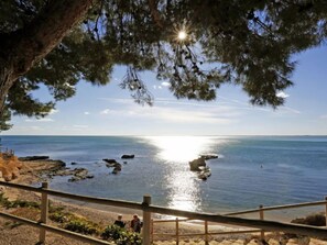 A coastal view with a wooden railing, rocky shoreline, and a clear sky. - Perales by Interhome (L'Ampolla)