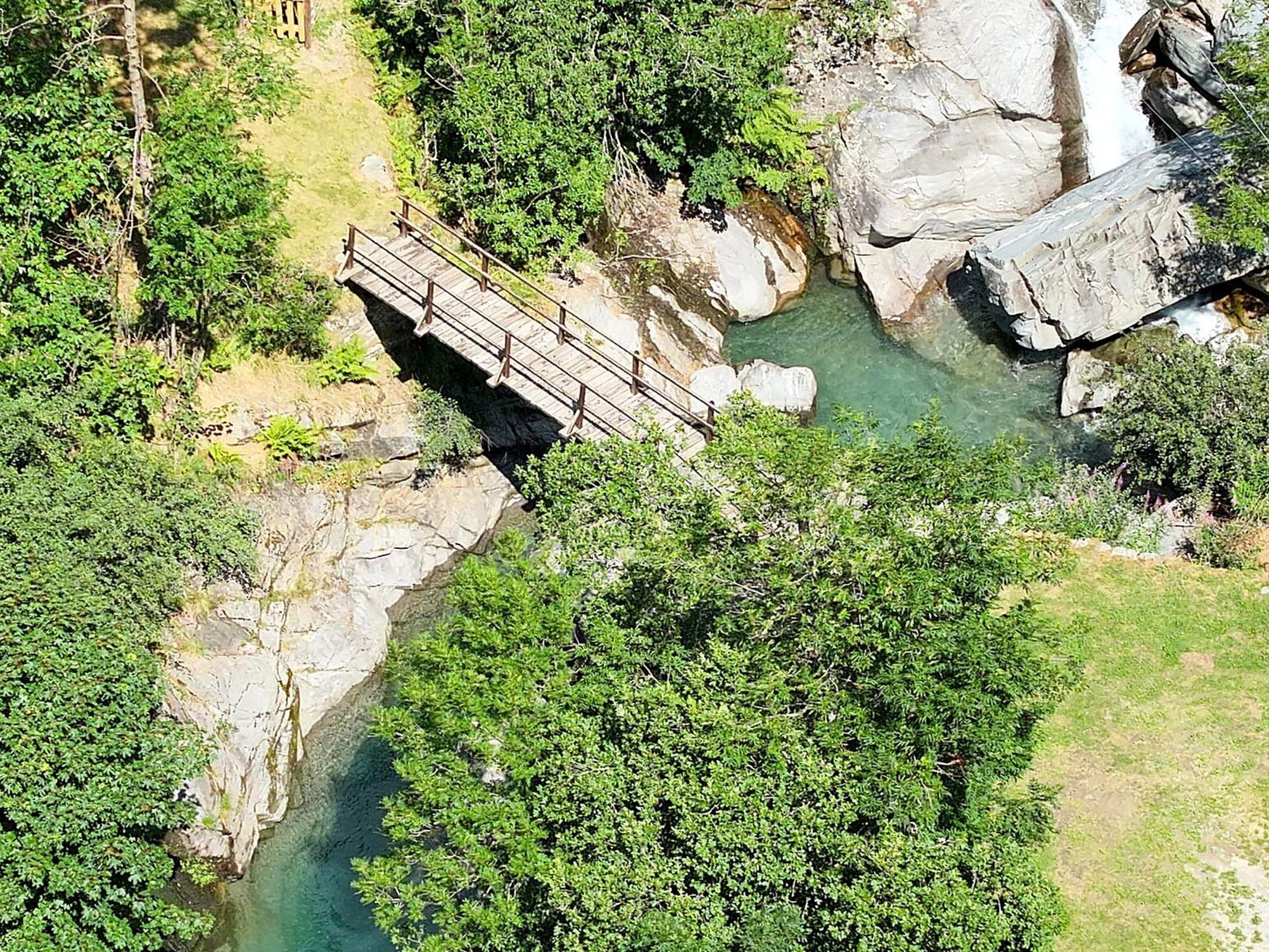 Un pont en bois enjambant une rivière, entouré de verdure.
