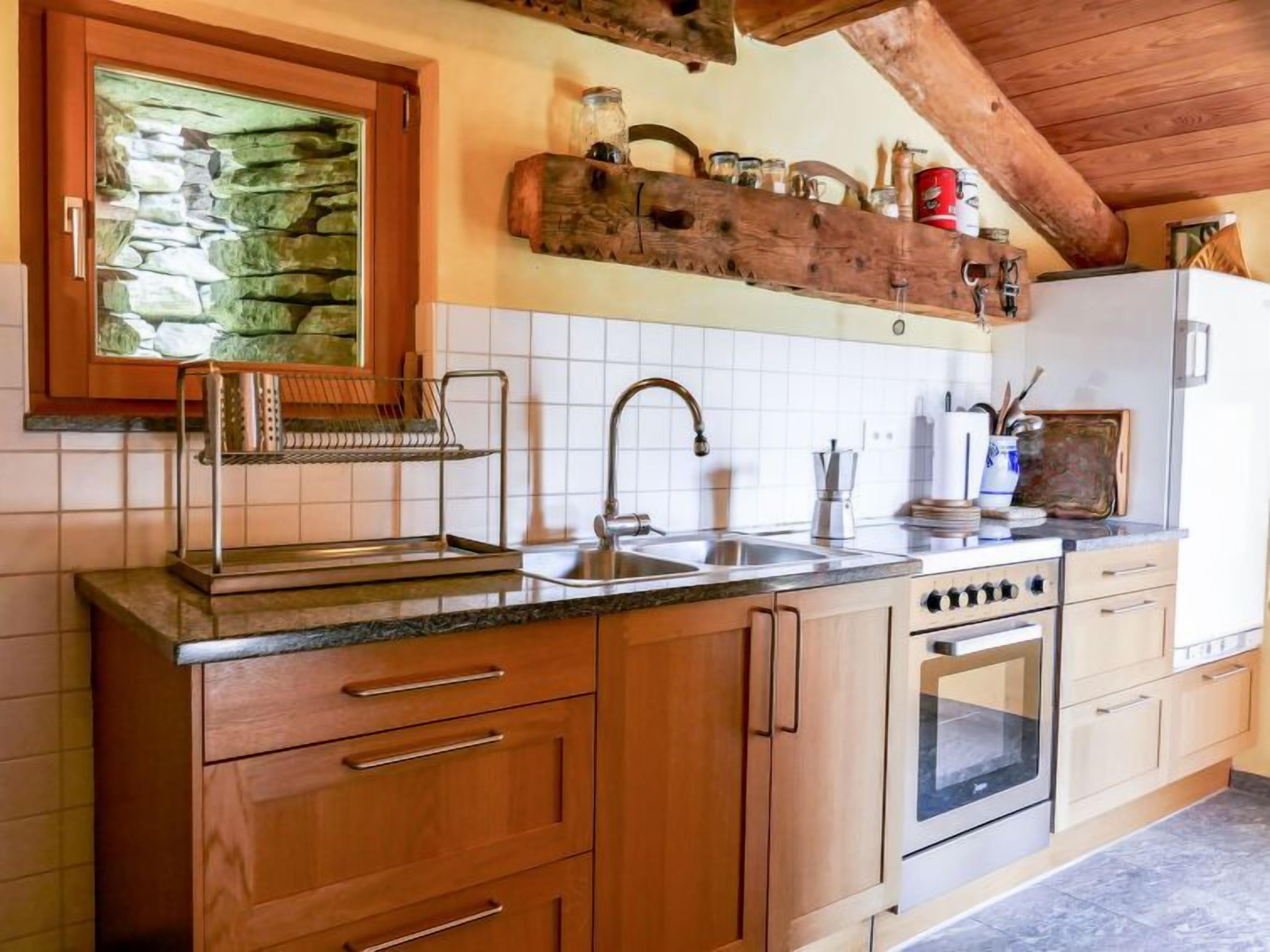 A kitchen with wooden cabinets, a stone backsplash, a built-in oven, and a hanging rack above the sink.