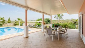 A covered outdoor area with a pool, lounge chairs, and a dining table with chairs. - Villa Pescada by Interhome (Albufeira)