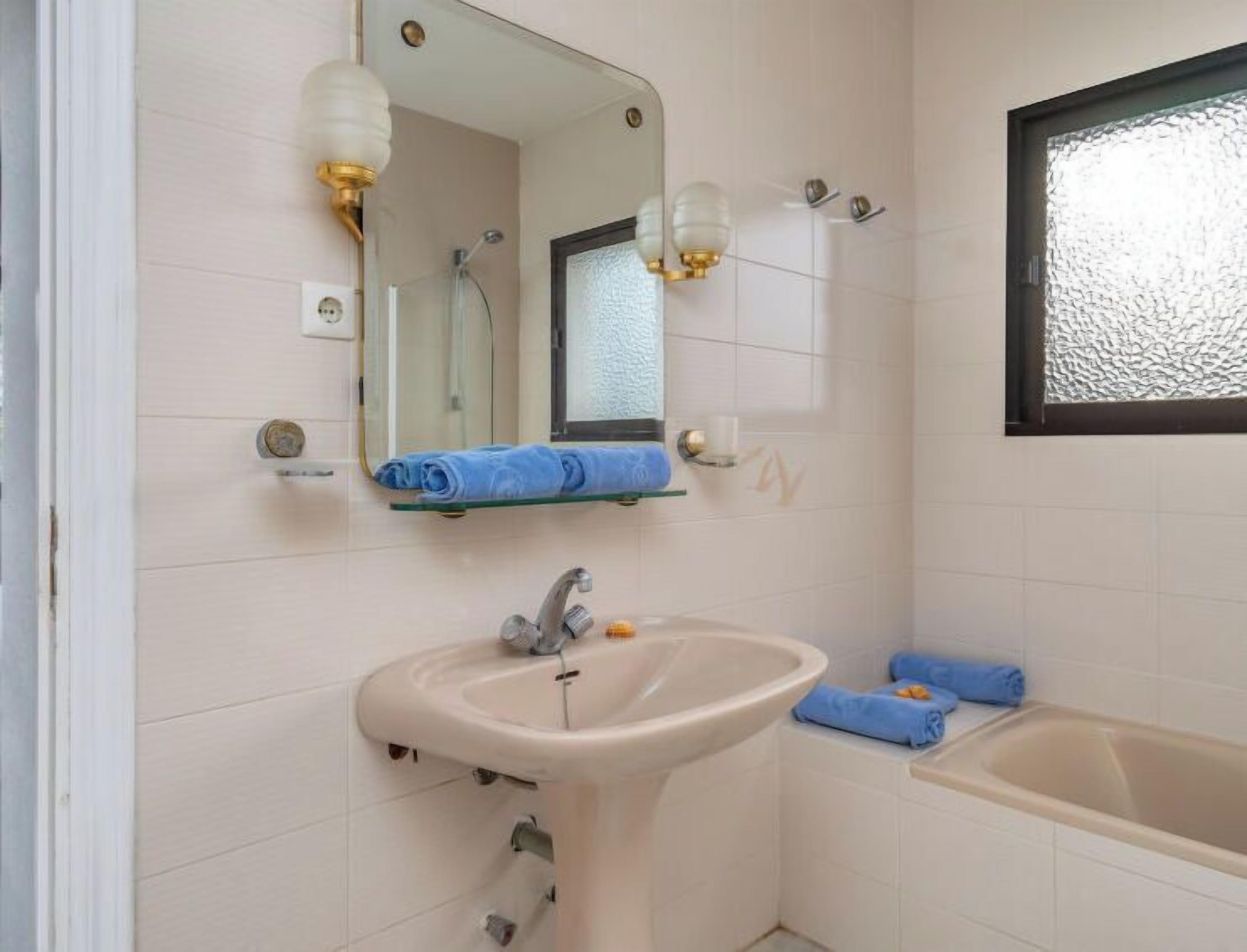 A bathroom with a sink, mirror, and bathtub.