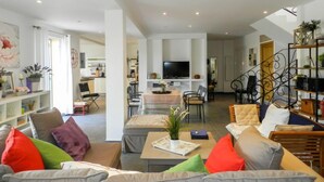 Een ruime woonkamer met een bank, salontafel en televisie. Een trap leidt naar een ander niveau.