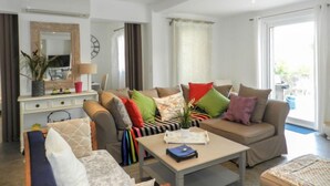 Een moderne woonkamer met een zithoek, een salontafel en een eetgedeelte met een spiegel en een plant.