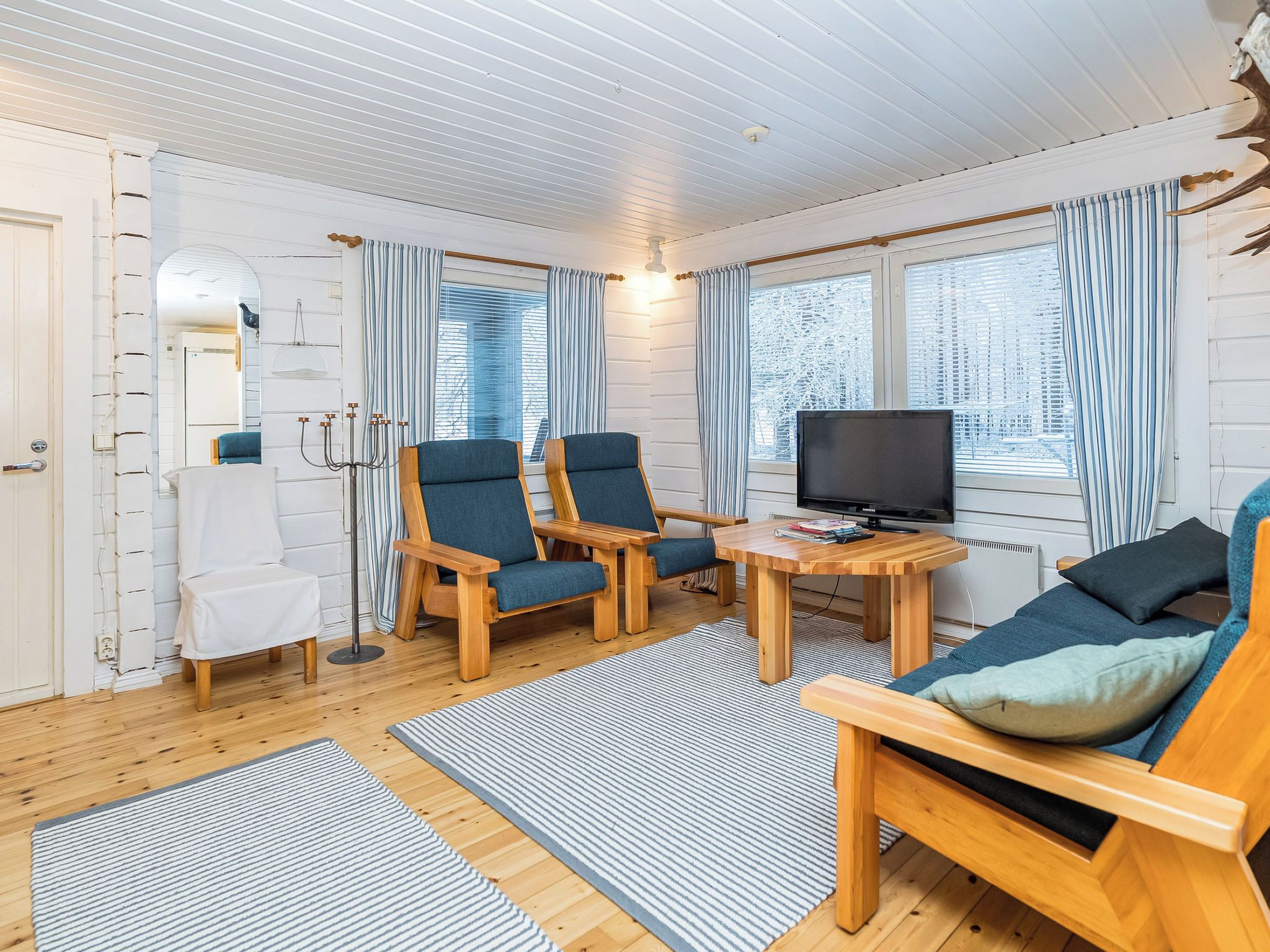 A cozy room with a television, two armchairs, a small table, and a sofa.