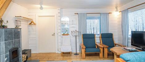 En hyggelig stue med pejs, to blå lænestole, et træbord og et fjernsyn.