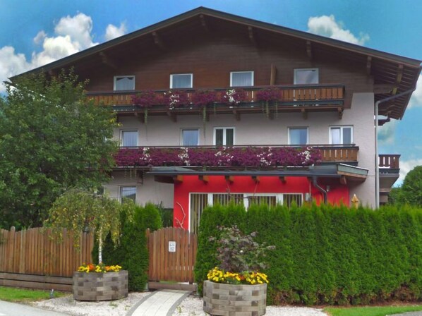 A multi-story hotel with balconies, a red awning, and a wooden fence.