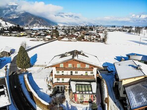 A snow-covered town with a prominent building featuring a large window and a balcony.