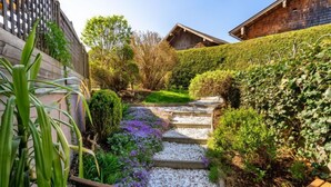 Ein Garten mit Steinstufen, die zu einer hölzernen Bank führen.