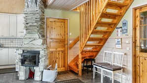 A cozy interior with a stone fireplace, wooden staircase, and a seating area. - Lustola a by Interhome (Sodankylä)