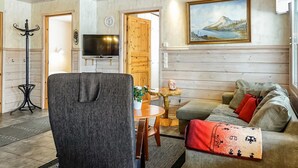 A cozy living room with a sofa, a television, a wooden ceiling, and a painting on the wall. - Lustola a by Interhome (Sodankylä)
