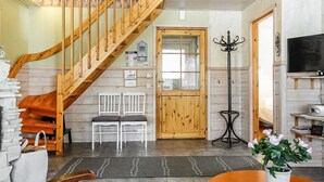 A cozy interior with a wooden staircase, two white chairs, a television, and a potted plant. - Lustola a by Interhome (Sodankylä)