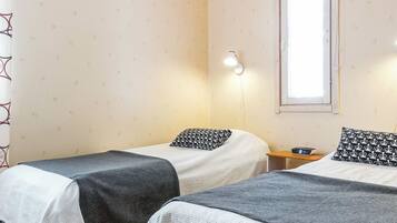 Habitación doble con dos camas, una mesita de noche, una ventana y una lámpara de pared.