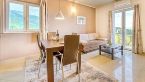 Een moderne woonkamer met een eetgedeelte, grote ramen en uitzicht op de omgeving.