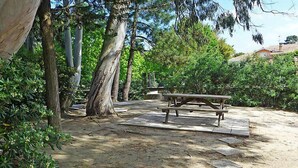A picnic area with a wooden bench and picnic table surrounded by trees and greenery. - Paradise Océan by Interhome (Capbreton)