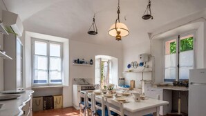 Een keuken met witte kastjes, een eettafel met stoelen, een fornuis en een koelkast.