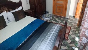 A bedroom with a bed, wooden wardrobe, and a door. - Riad Drissia (Fes)