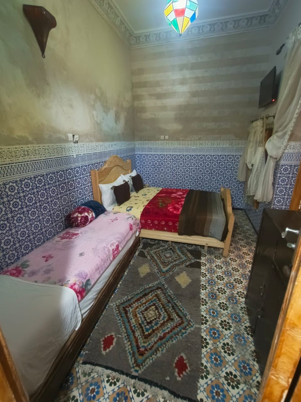 A small, single-bed room with patterned walls and a tiled floor.