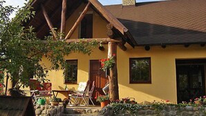 A rustic house with a stone wall, wooden porch, and a chimney. - Marylin by Interhome (Marylin)