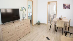 En moderne stue med et fladskærms-tv, møbler i træ og et spiseområde.