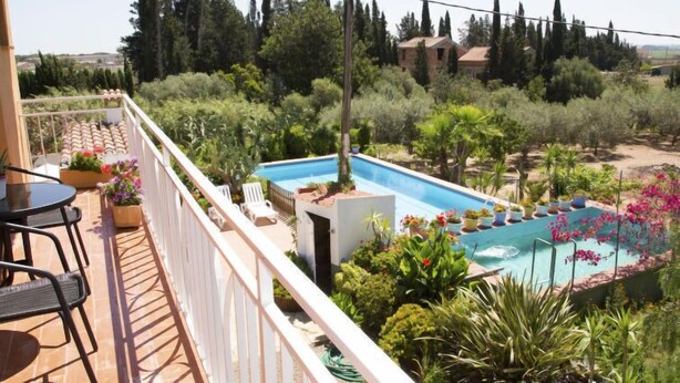 En balkon med swimmingpool, omgivet af frodig vegetation og udsigt over landskabet.