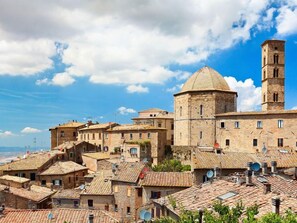 A historic town with stone buildings, a prominent church with a dome and bell tower, and a clear blue sky.