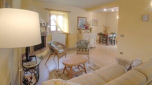 Ein gemütliches Wohnzimmer mit einer Couch, Sesseln, einem Esstisch und einem Kamin.