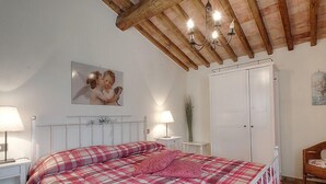 Ein Schlafzimmer mit einem Bett, Nachttischen, einem Kleiderschrank und einer Chandelier.