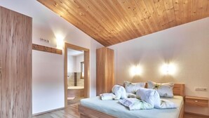 A bedroom with a wooden ceiling, a bed with floral bedding, and a nightstand.