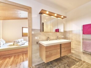 A modern bathroom with a wooden vanity, a large mirror, and a dual sink.
