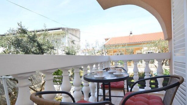 A balcony with wicker chairs and a small table, surrounded by white balustrades. - Apartment Mladen by Interhome (Vodice)
