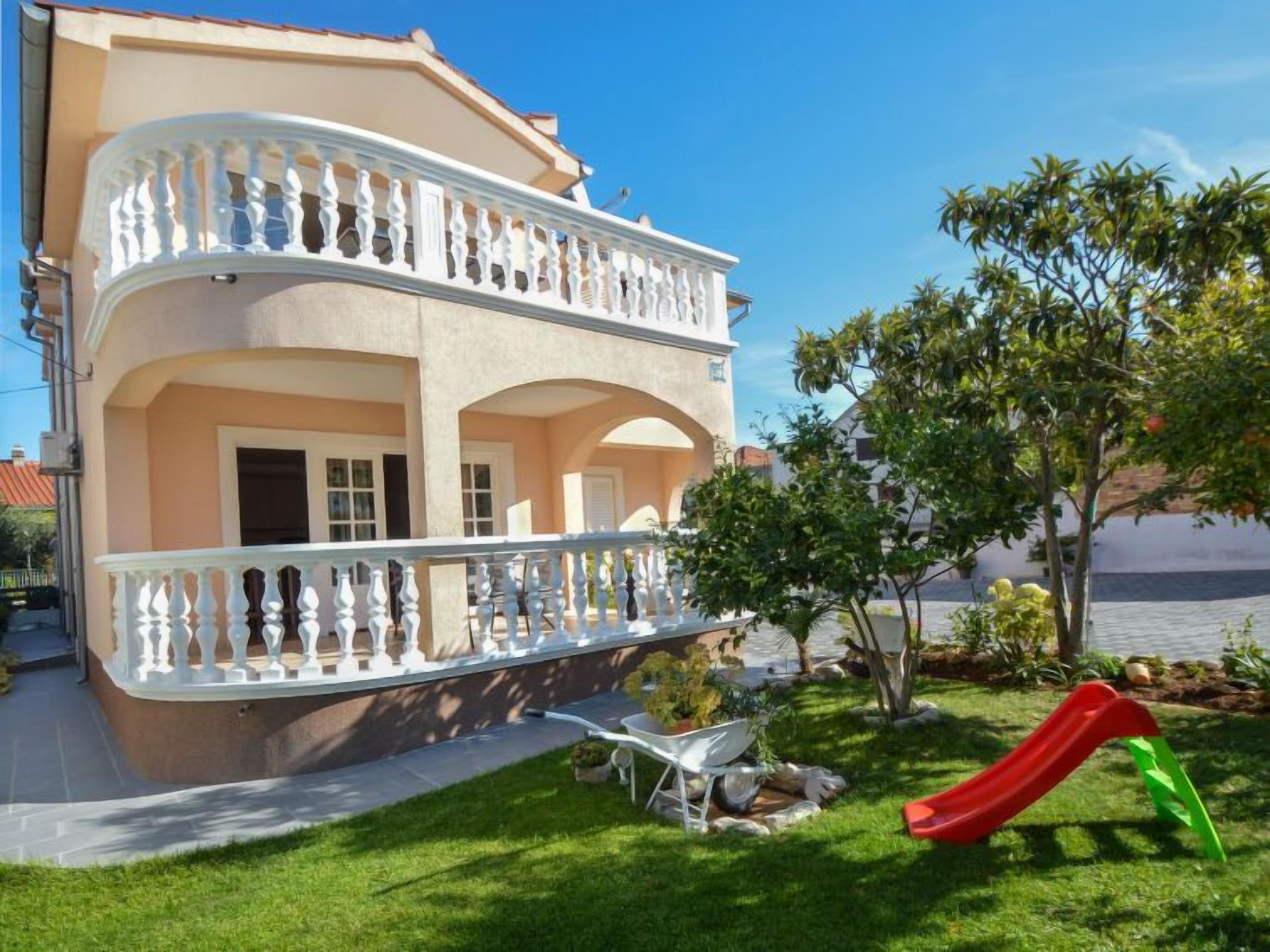 A two-story building with a balcony, a slide, and a garden.